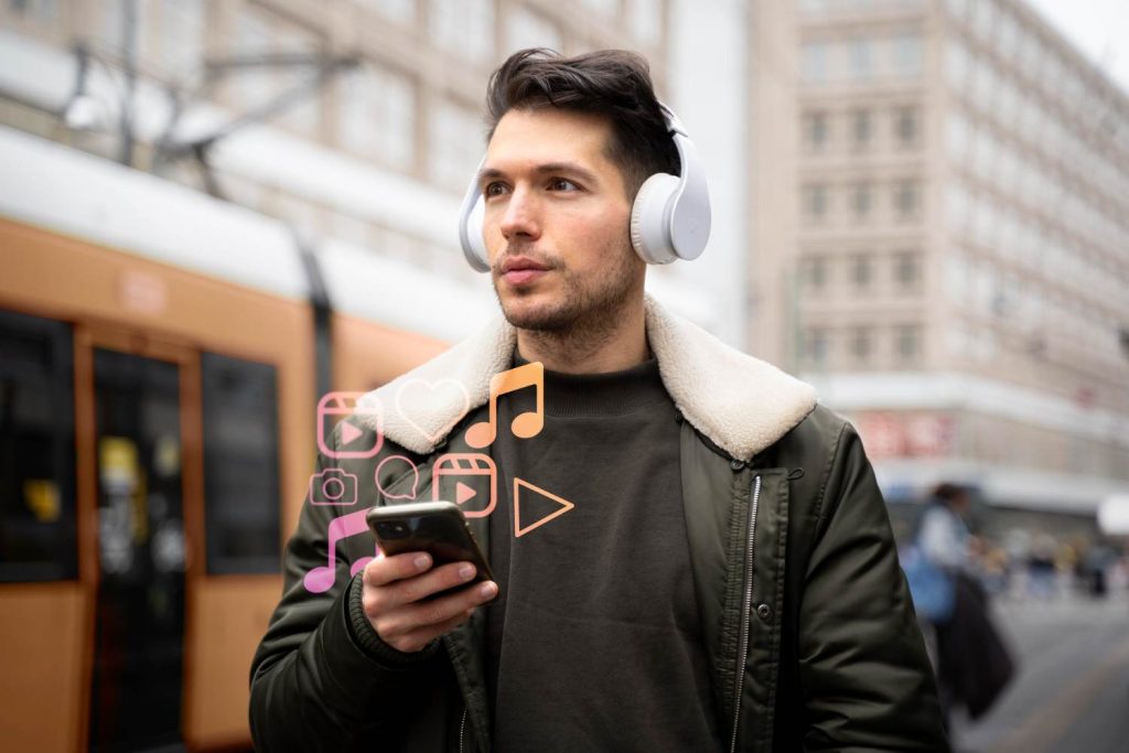 A person wearing headphones stands outdoors, focused on their smartphone with social media and music icons graphics nearby.